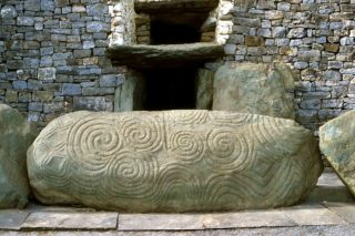 Newgrange Entrance stone which consists of a large triple spiral engraved with double loops which fill the left side