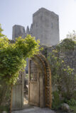 an arched doorway set within a wall is open leading toward the castle, which is looming above in the background.