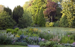 Early summer view of the lake at Altamont Gardens surrounded by lush planting and trees