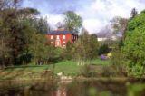 Front façade of Glebe House with planting near the entrance, lake in the foreground and the Glebe Gallery in the background