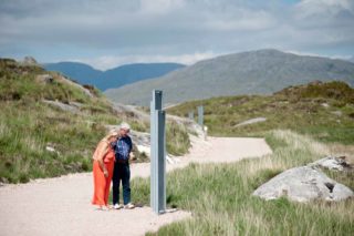 Two people stop at the wayfinding along the Ionad Cultúrtha an Phiarsaigh Walkways