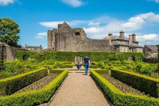 The lush green walled garden at Roscrea, with a woman walking through the grounds facing the castle exterior