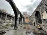 the rain soaked courtyard of the church, with the original arched wall in the centre, and flat tombstones marking the ground