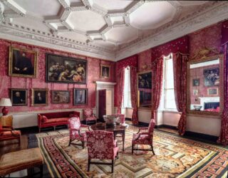 A glimpse of the Red Drawing Room after conservation of the silk wall hangings, showing the fabulous picture hang and the new curtains and upholstery made of silk reproduced to match the original