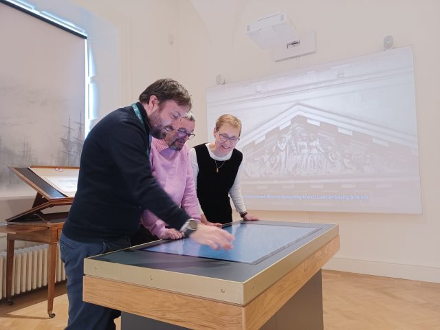 Guide giving tour to two visitors within interior exhibition of the Custom House