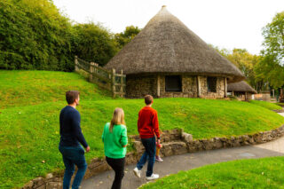 Visitors walk by Lough Gur huts