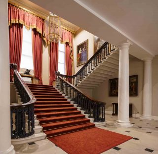 The grand staircase draped in red carpet leading up to the state apartments of the castle