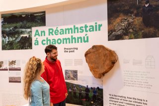 Two visitors look at an exhibiton about bogs preserving the past in a visitor centre at the Céide Fields
