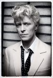 A black and white image of a young David Bowie taken by Denis O'Regan. It is a portrait pose of his head and upper body. Bowie is wearing a light suit with an open black bow tie. His hair is fair and tousled and he is wearing a wry expression.