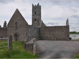 A close up of the ruins of Rosserk. The chapel and tower walls remain intact, although there is no roof. In the back, right corner of the image you can see the River Moy