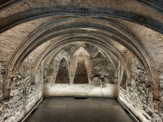 This chapter house within the medieval abbey contains a low vaulted ceiling and the room is lit in artificial light