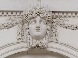 On a central keystone of the Custom House exterior is a face representing the River Liffey. It is depicted as female, with ropes and braids adorning its head and wrapping under her chin, and fruit flowing above her forehead to signify abundance.