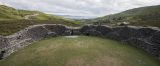 The interior of the stone fort, with a circular stone surround and grass in the centre, backdropped by a valley