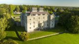 Aerial photograph of Portumna Castle, focusing on the building's 17th century facade. There is green grass and trees in the foreground of the photograph