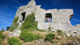 A family look out of a window-like platform from the ruins of Dunamase