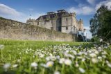 two people walk through the grounds on the other side of the wall where the castle stands on the left