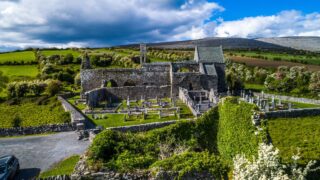 A panoramic view of Corcomroe Abbey nestled within the valley of the Burren mountains