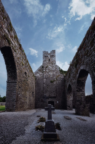 The interior ruins of Corcomroe Abbey, with a cross placed in the foreground