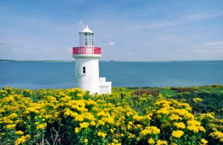 Looking upriver over the lighthouse on Scattery Island at the mouth of the River Shannon estuary County Clare