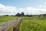 The surrounding green fields and bright blue sky backdropping the ruins of Abbeyknockmoy