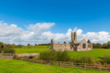 Kilmallock abbey surrounded by lush green fields and a bright blue sky