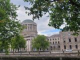 view of the dome of the four courts from across the river, with trees shrouding the view slightly