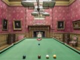 The pool table in Farmleigh House, ornate portraits and red wallpaper decorate the walls.