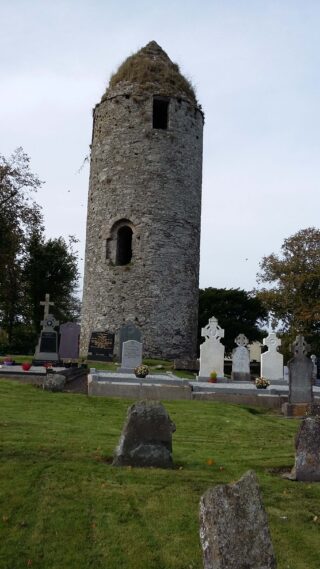 the small, stone round tower, with some crosses and tombstones in the foreground