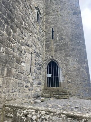 A close-up to the gated entrance door of the castle, hidden in the crease of the building's L shape