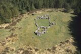 aerial view of two circular shapes of stones, making up a passage tomb. Set within a clearing in a forest.