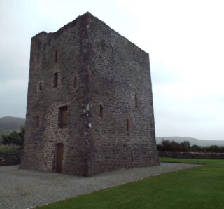 the dark stone of the castle standing stark against the white clouded sky