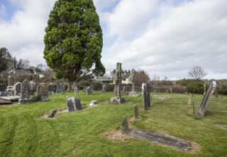 a tree and gravestones act as the surrounding scenery to the two high crosses.