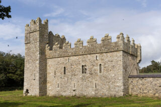 exterior view of the castle, complete with a taller tower on one end, and the attached body of the castle, which is a long rectangular shape.