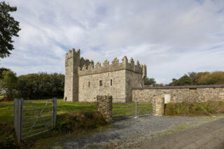 exterior view of the castle, complete with a taller tower on one end, and the attached body of the castle, which is a long rectangular shape.