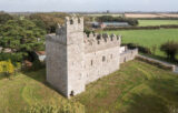 aerial view of the exterior of the castle. The surrounding landscape is of trees and divided fields.
