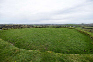 interior of a ringfort, a small wall of stones making the ring, and grass filling it inside and outside