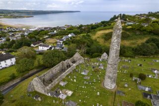 aerial view of the Ardmore site, with the round tower on the right, the roofless cathedral on the left, and the graves dotted around both monuments.