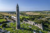 aerial view of the round tower looming above the cemetery and cathedral. The surrounding houses and fields are visible as far back as the horizon.