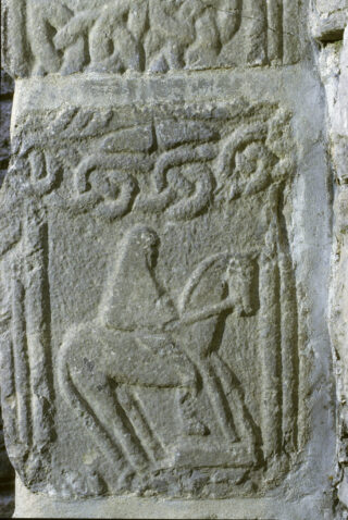 carving on stone of a person sitting on a horse