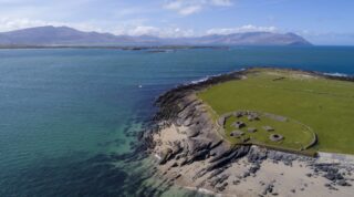 view of the remains of a monastic site sitting on the edge of an island in the middle of the ocean