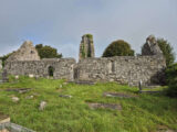 external view of the remaining ruins of Drumcliffe Church, with both flat and standing gravestones surrounding the stone walls of the church