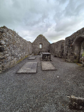 interior view of the remains of the church, with the grey clouds above matching the grey stone of the ruins.