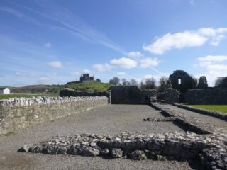 a view of the Rock of Cashel from the abbey grounds. The cashel is in the distance, perched on a hill-top, reaching for the blue sky.