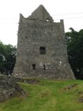 portrait view of a stone castle standing atop a small grassy mound