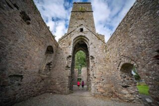 internal view of the abbey. Looking at the tower from below. Two women walk through the archway just under the tower.