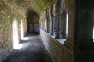 the internal corridor of the cloisters, light shining through each of the arches