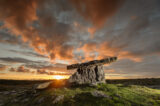 stone tomb backdropped by a dramatic orange-tinged sky, the clouds floating so close to the ground.