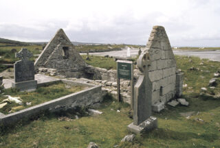 a roofless ruin of a church situated within a surrounding graveyard