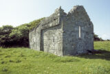 the ruins of a church stand alone within a field