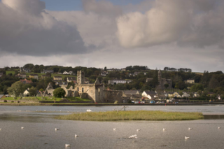 view of the friary from across the river, as part of the overall surrounding village.